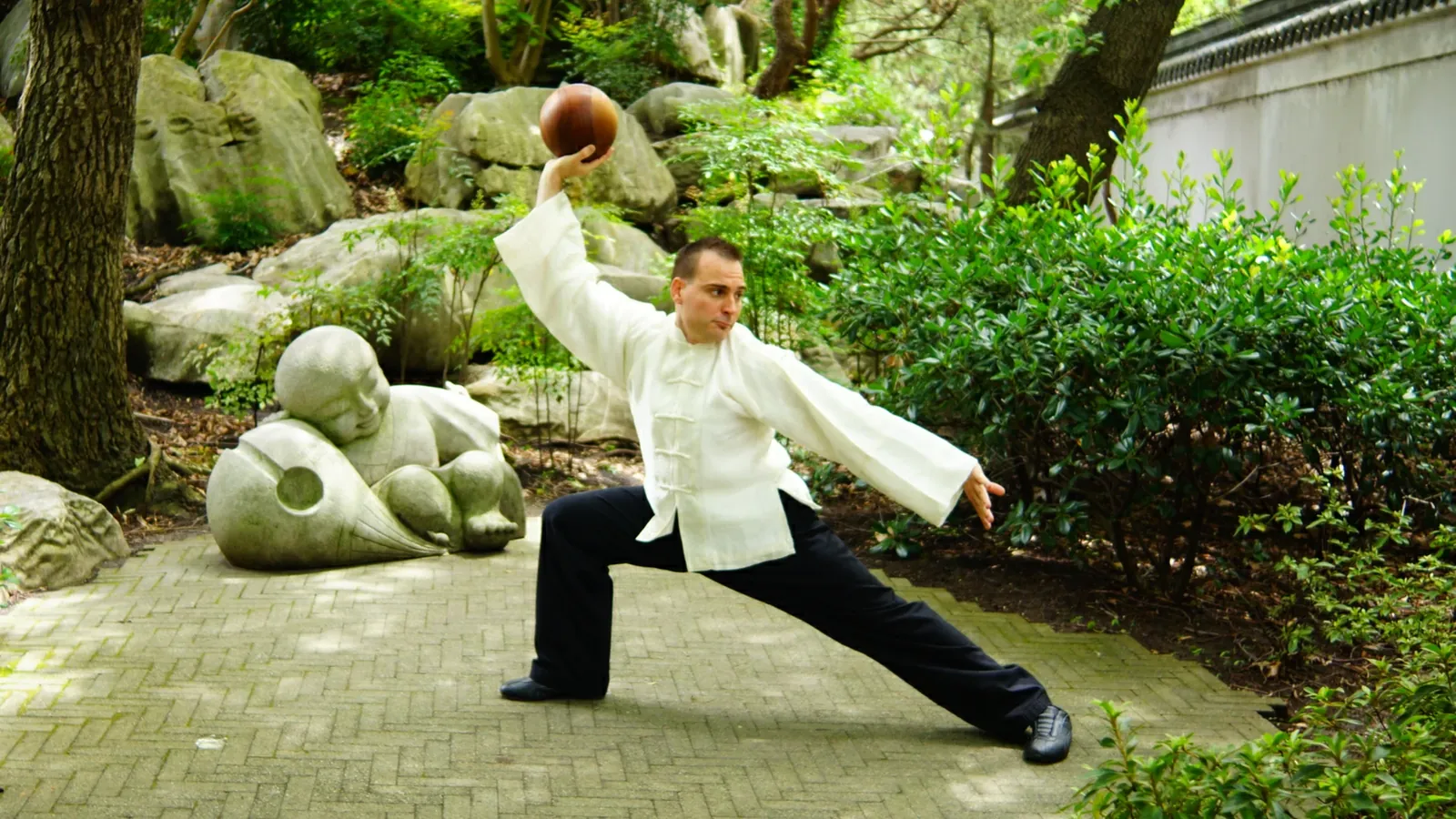 Head Instructor Grant Mundy performing a Tai Chi Ball Qigong posture in a garden
