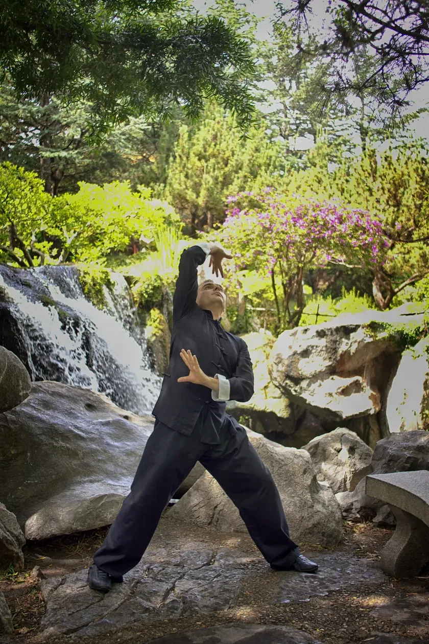 Grant Mundy performing the Heaven Palm posture beside a waterfall garden
