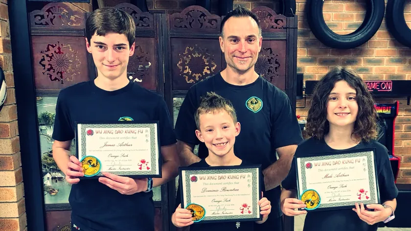 Three Little Dragons students holding their grading certificates with Head Instructor Grant Mundy