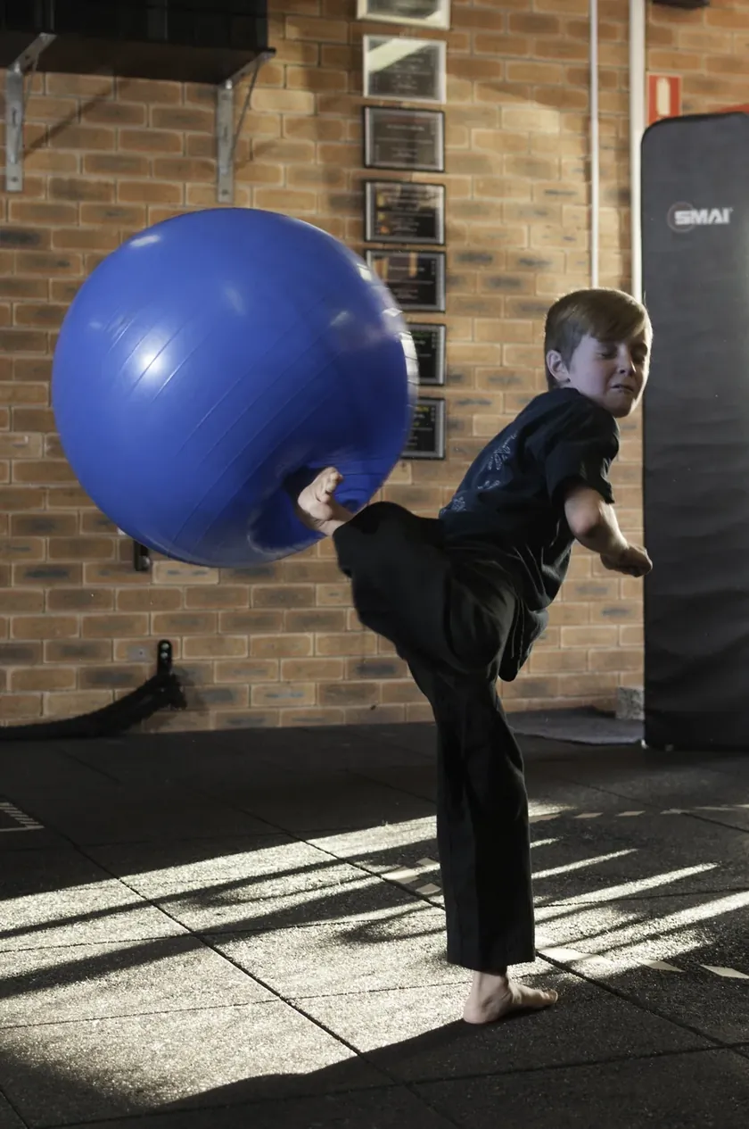 A Little Dragons student kicking a large exercise ball