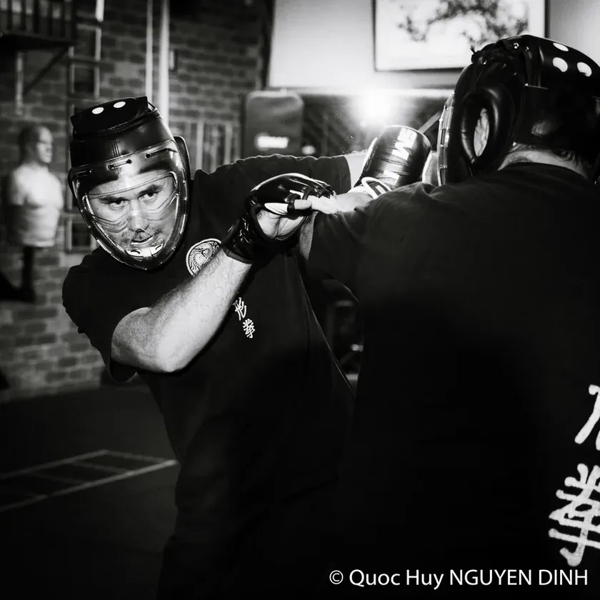 Adult students sparring with head gear at Wu Xing Dao, in black and white