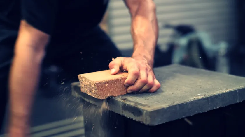 Close-up of a palm strike breaking a brick, dust flying