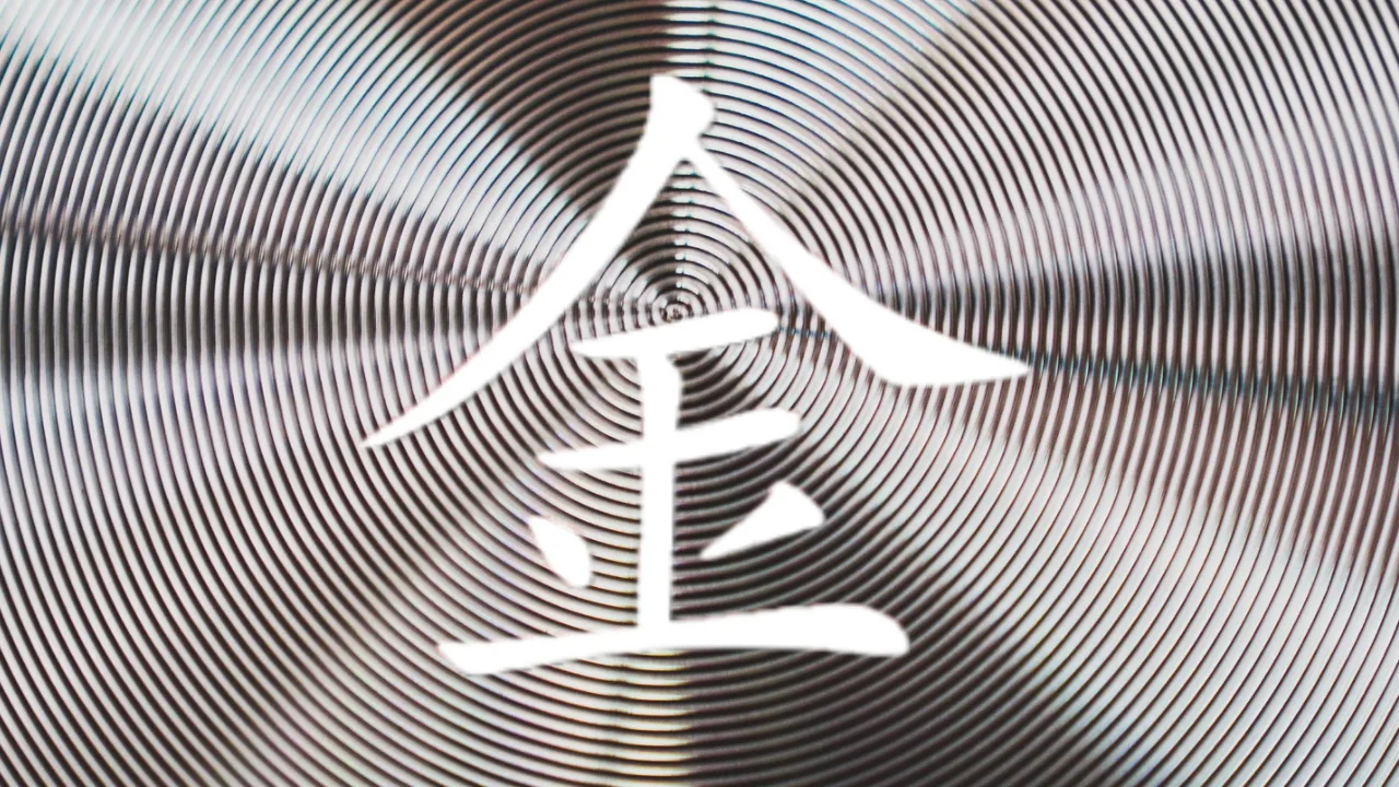 White Chinese character for the word 'Metal' centered over a black-and-white concentric spiral pattern, creating an optical illusion.