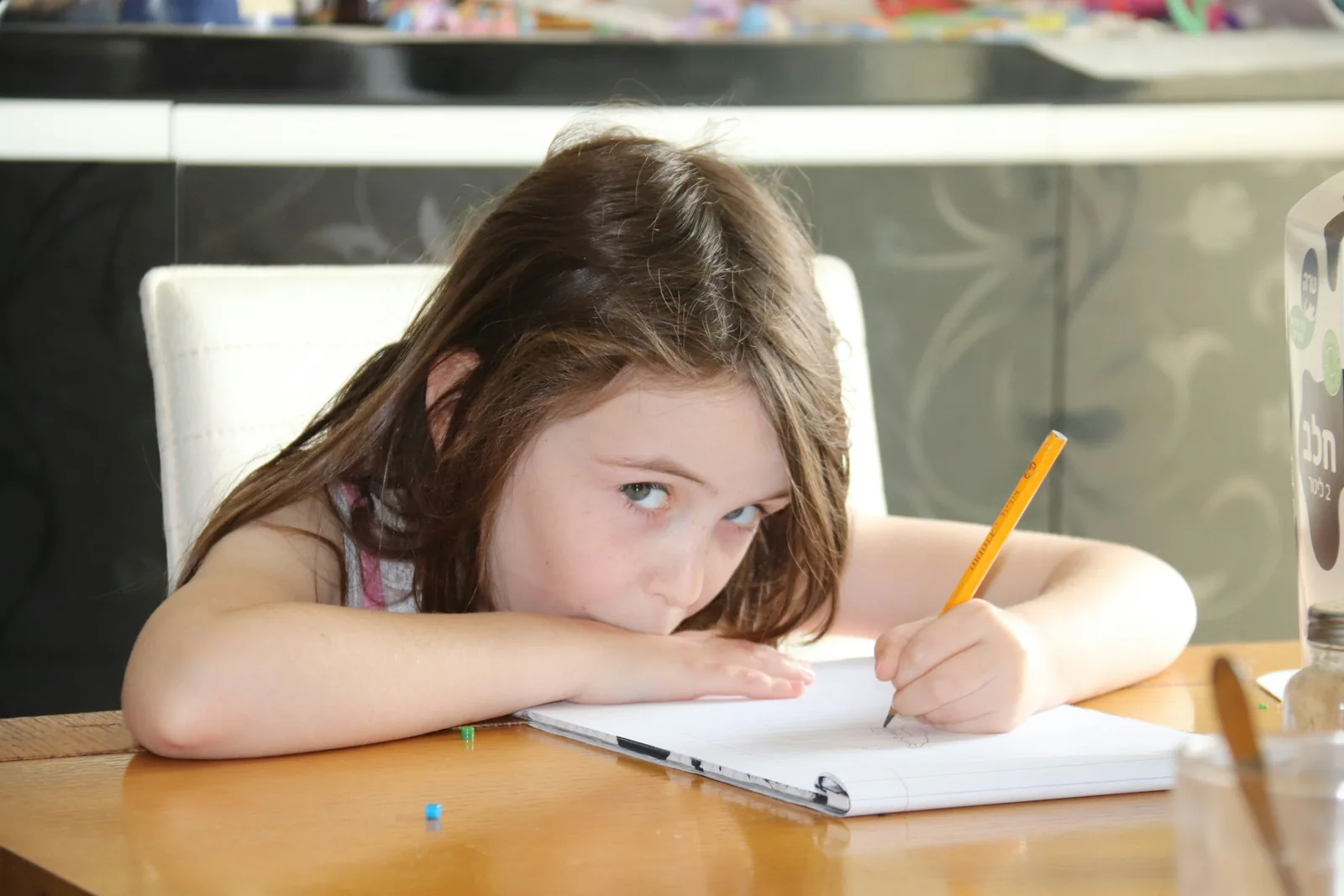 A young girl frustrated at her homework, head in her hands at a desk.