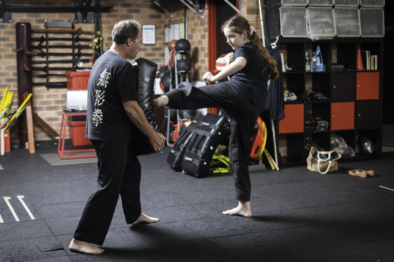An adult student holds kick pads for a training partner at Wu Xing Dao kung fu in Wyoming NSW.