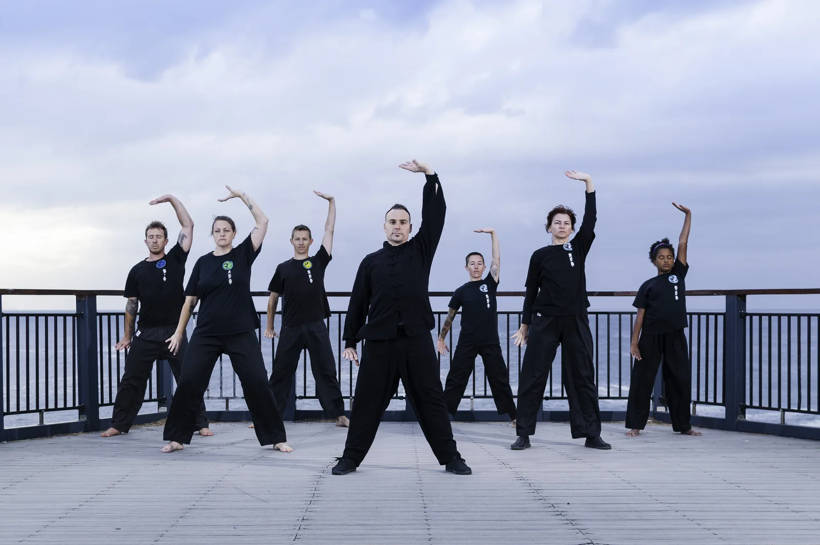 A group of Wu Xing Dao students practise Qigong together on a seaside lookout at Terrigal.