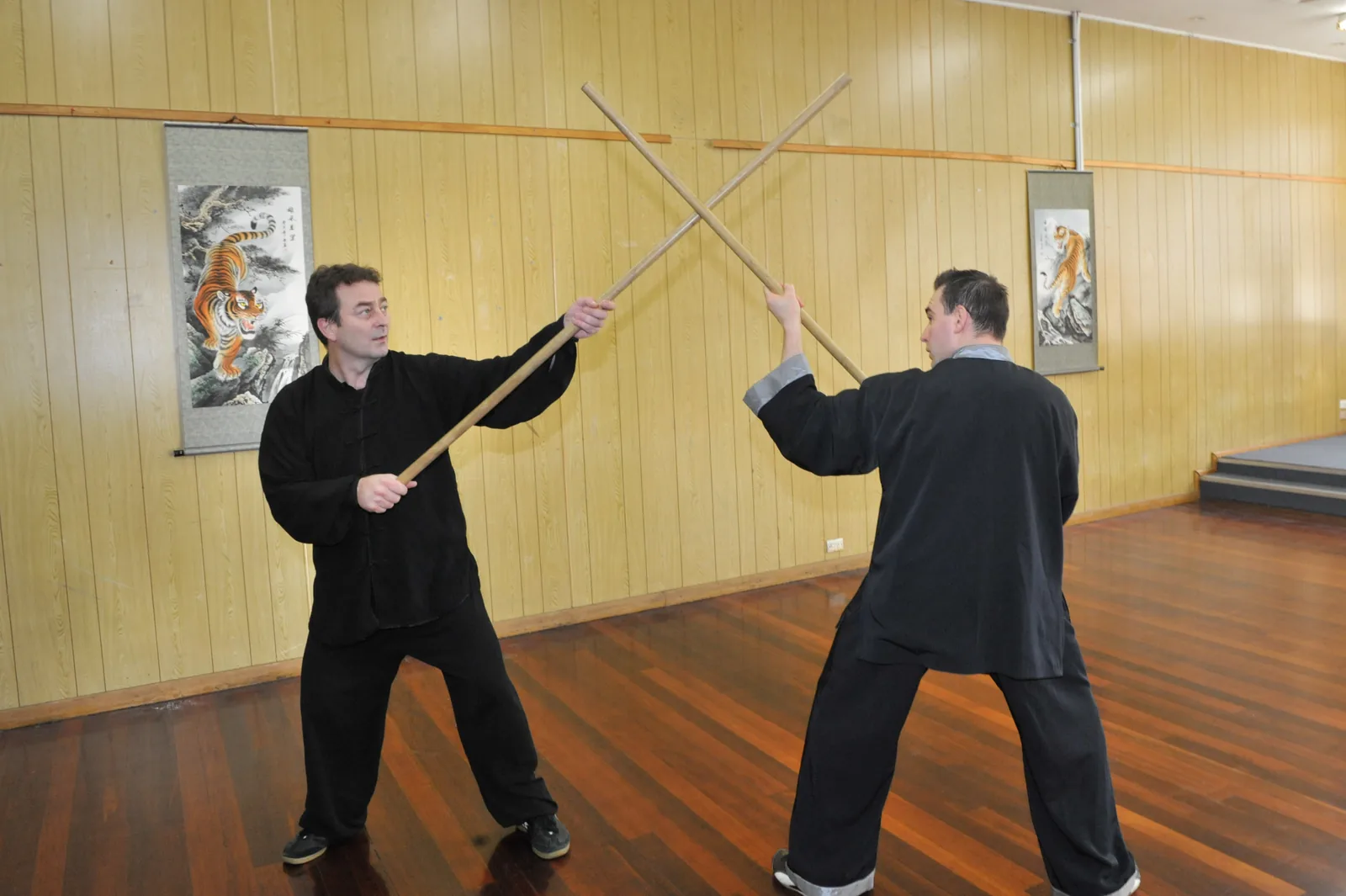 Two students practise a staff partner drill in the training hall.