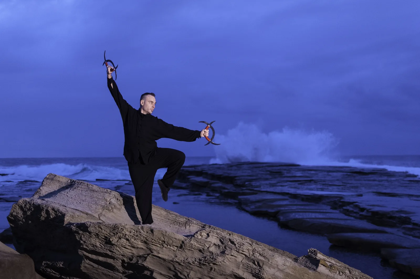 Weapons practice on the sea rocks at Terrigal under a stormy sky.