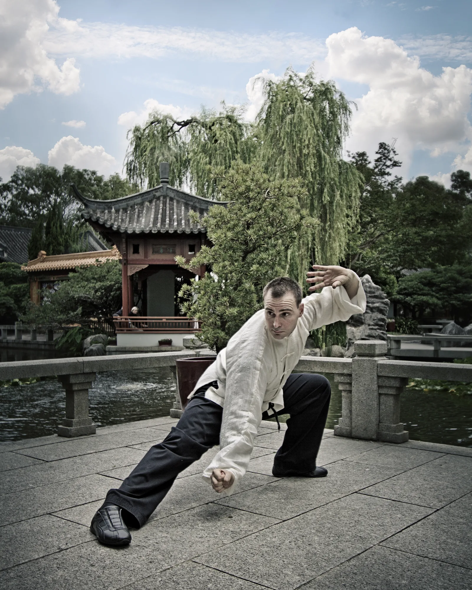 Tai Chi practice in a Chinese garden: a rising fist movement in white silks.