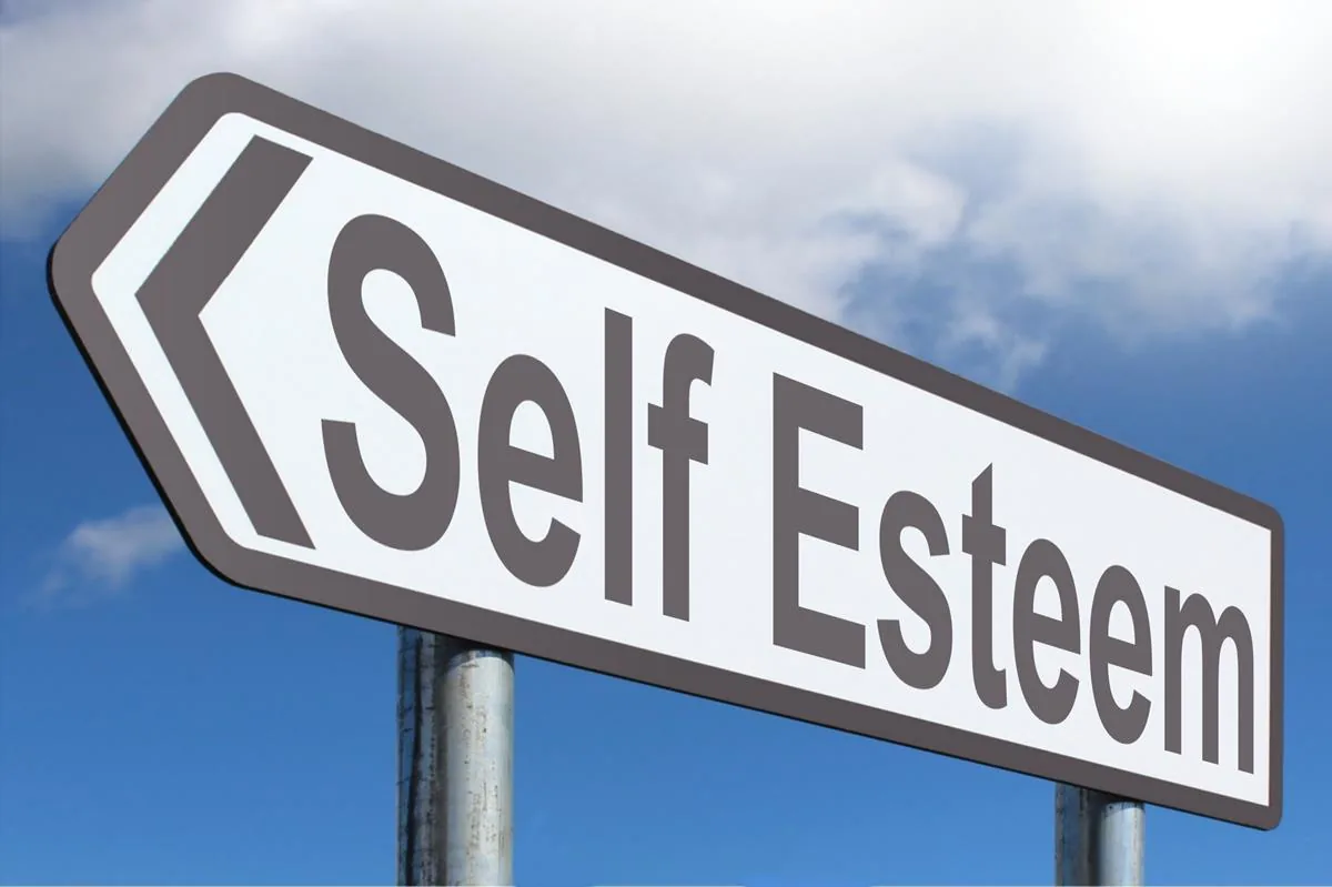 Road sign with left arrow and the words Self Esteem against a blue sky