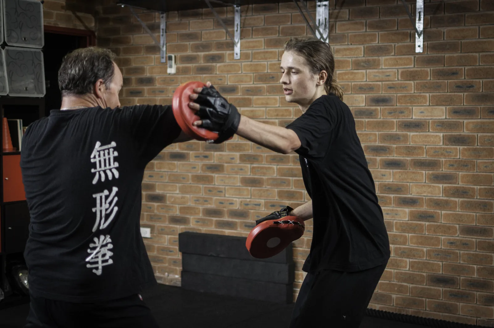 A new student punches focus mitts held by an instructor at Wu Xing Dao kung fu.
