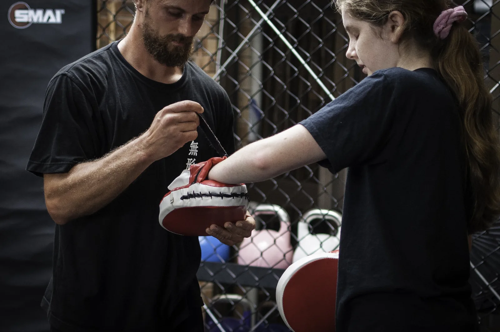 A young woman strikes a focus mitt during a beginners kung fu class.