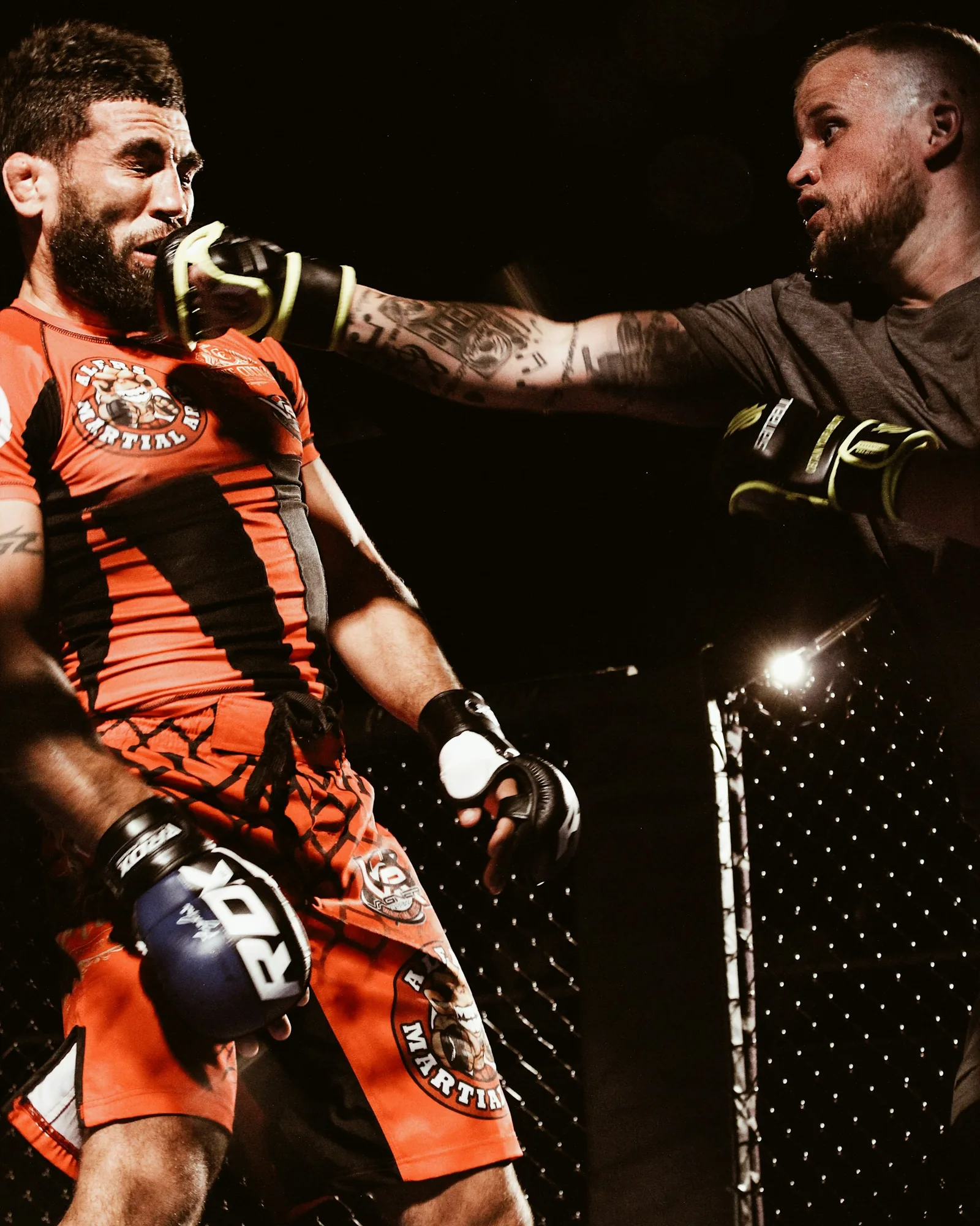 Two MMA fighters exchange strikes inside a cage.