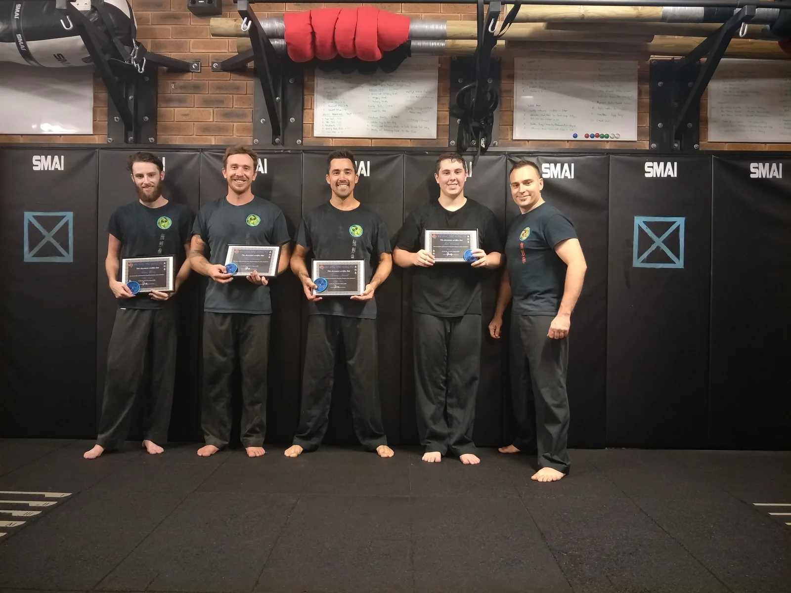 Adult students hold their grading certificates in the kung fu school.