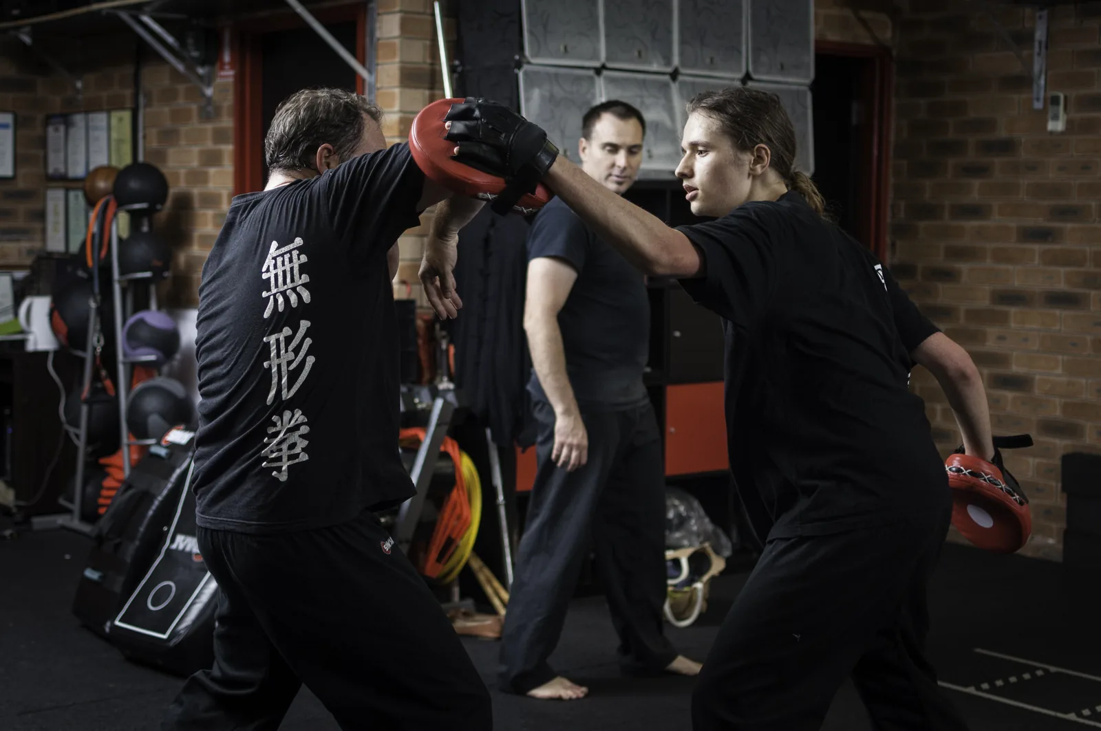 A student strikes focus mitts during pad work.