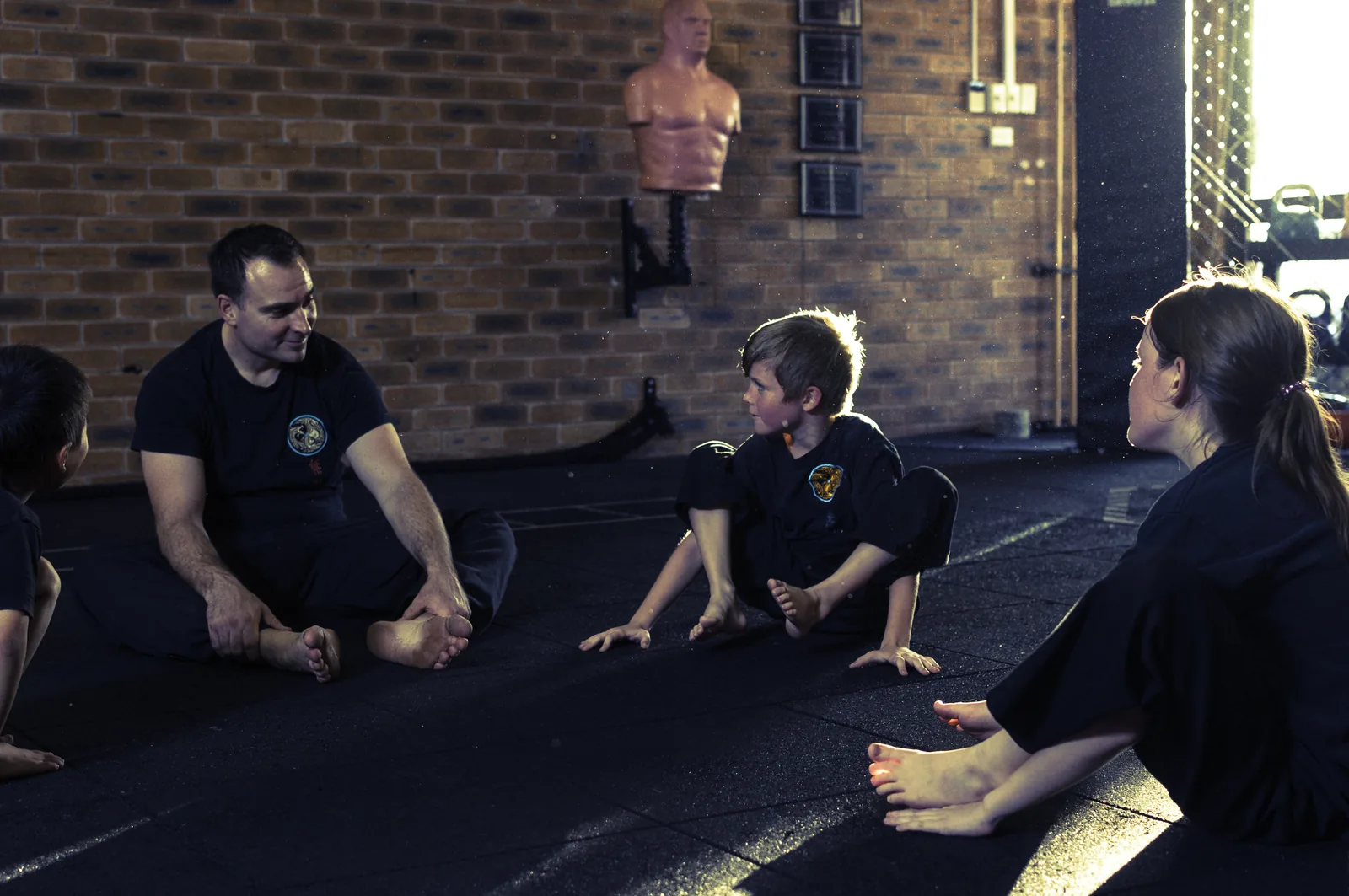 An instructor sits with young students during a Little Dragons class.