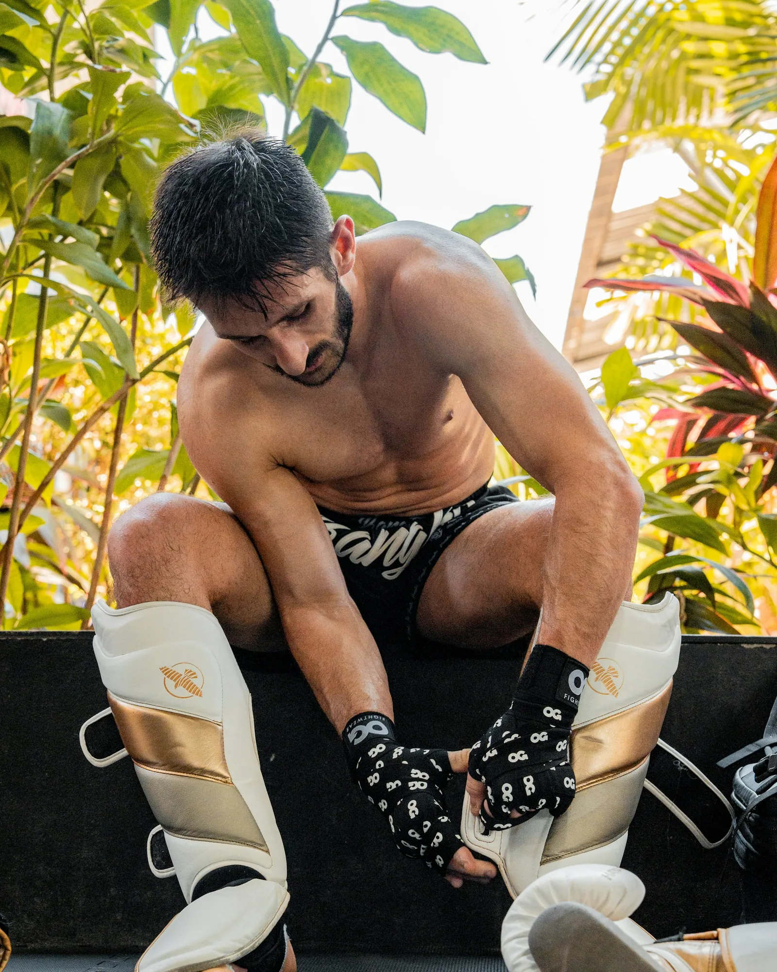A fighter straps on shin guards before training.