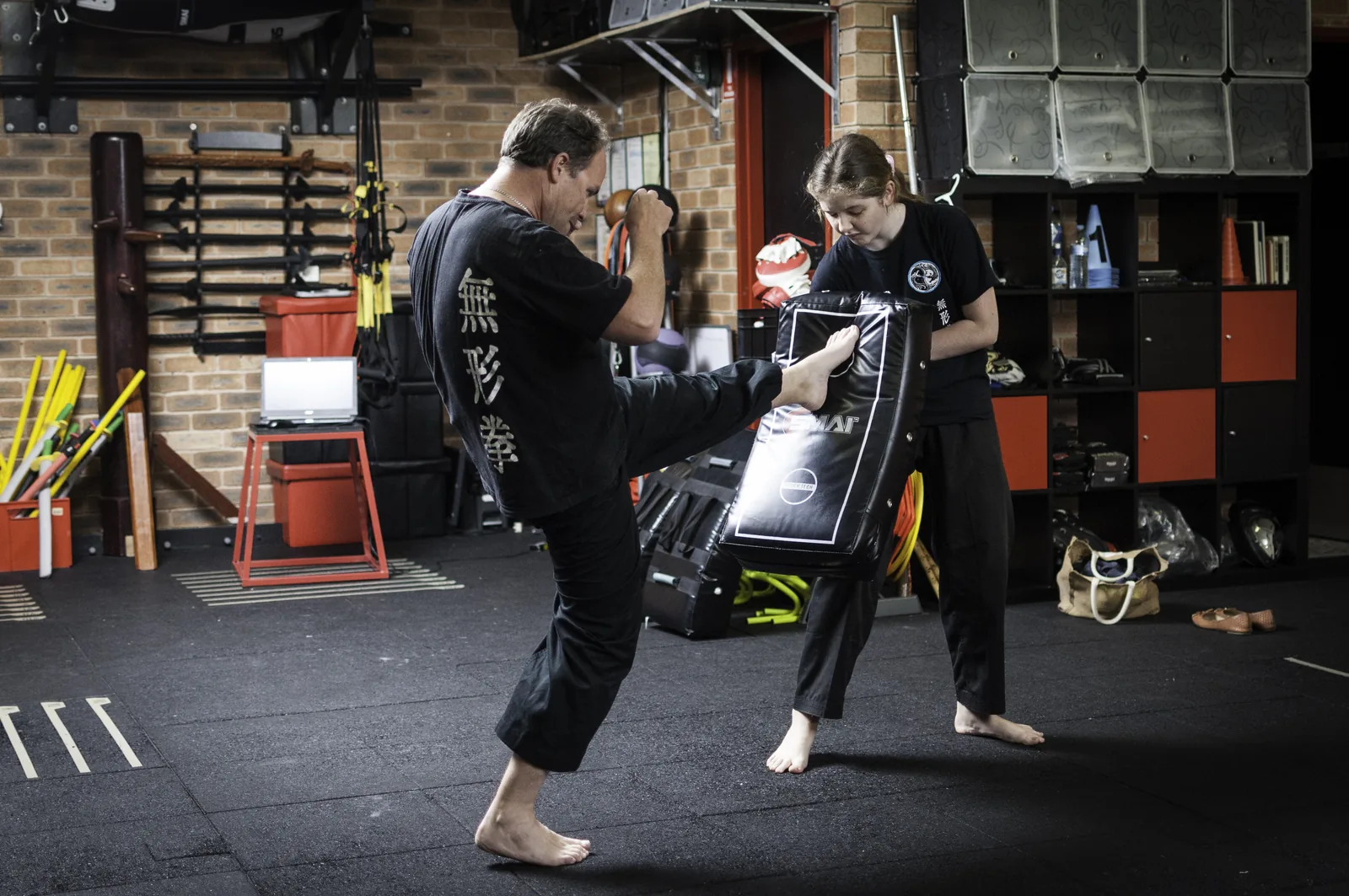 A student kicks a kick shield held by a training partner.
