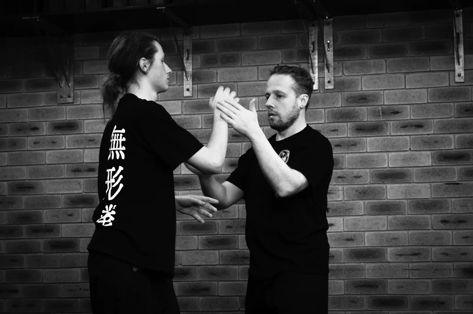 Two students practise chi sau (sticky hands), in black and white.